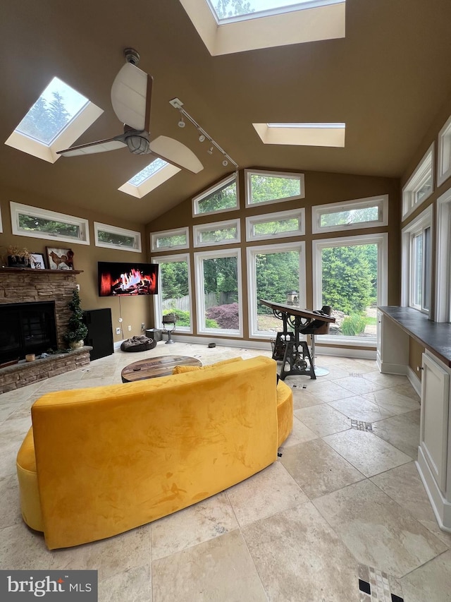 living room with vaulted ceiling with skylight, a fireplace, and ceiling fan