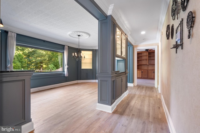 corridor with light hardwood / wood-style flooring, a chandelier, and ornamental molding