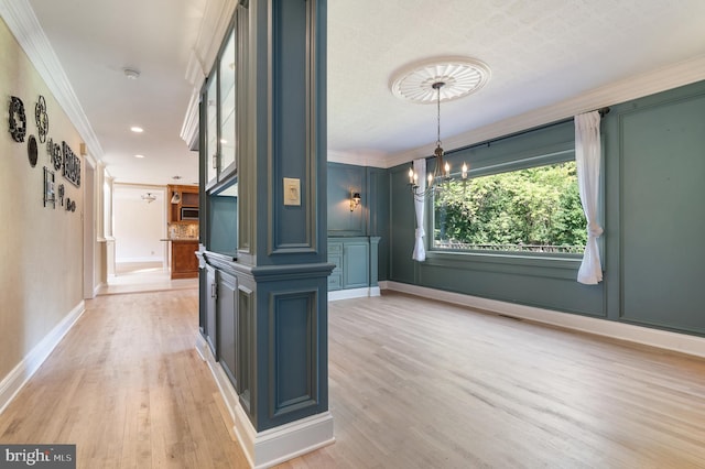 interior space featuring an inviting chandelier, light wood-type flooring, and crown molding