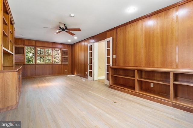 interior space featuring crown molding, light hardwood / wood-style floors, wooden walls, and ceiling fan