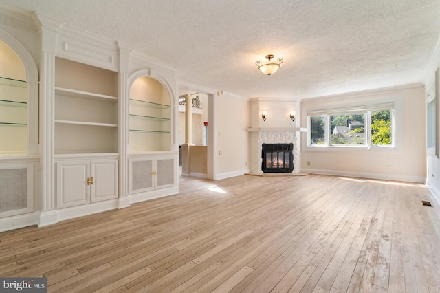 unfurnished living room with a textured ceiling, a high end fireplace, and light hardwood / wood-style flooring