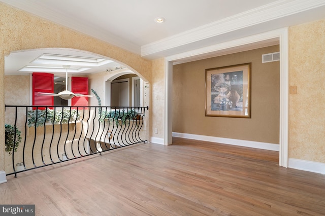 empty room with a tray ceiling, crown molding, and hardwood / wood-style floors