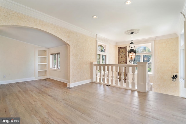 empty room featuring crown molding, light hardwood / wood-style floors, and built in shelves