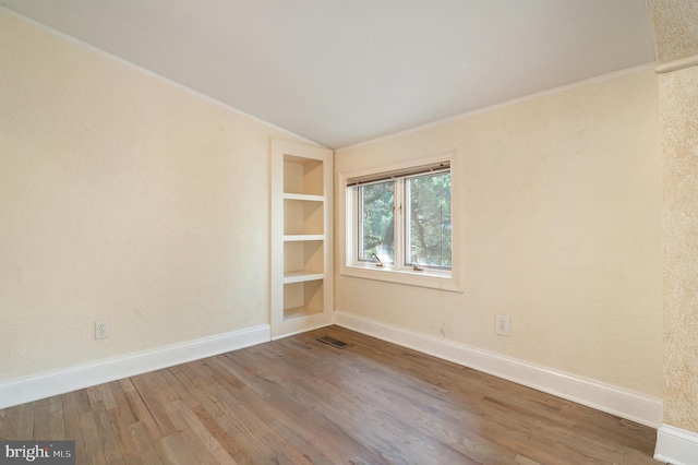 empty room featuring lofted ceiling and hardwood / wood-style flooring