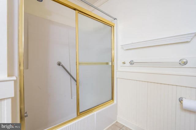 bathroom with bath / shower combo with glass door and tile patterned floors