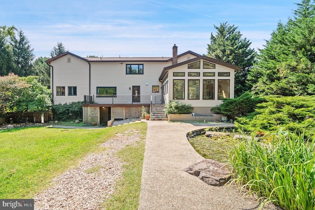 back of property featuring a lawn and a wooden deck