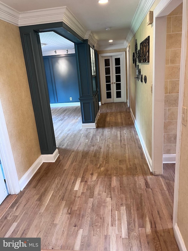 hallway with wood-type flooring, crown molding, and french doors