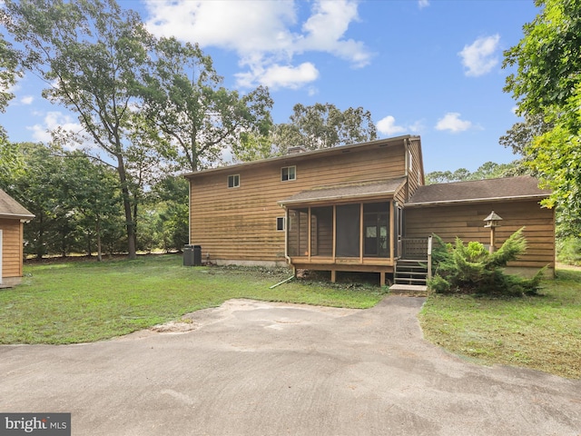 back of property with a lawn, a sunroom, and central AC unit