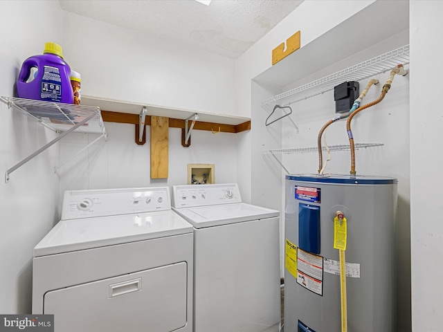 clothes washing area featuring washing machine and clothes dryer, a textured ceiling, and water heater