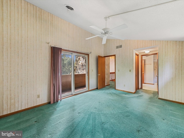 empty room with vaulted ceiling, a textured ceiling, ceiling fan, and carpet