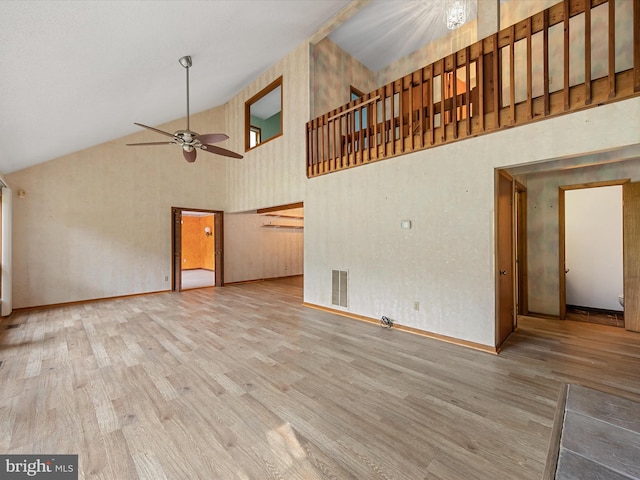 unfurnished living room featuring wood-type flooring, ceiling fan, and high vaulted ceiling