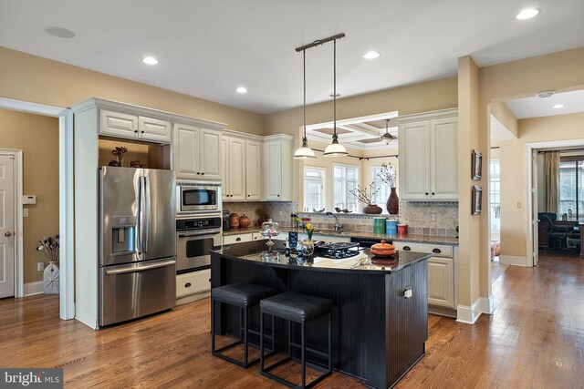 kitchen with appliances with stainless steel finishes, white cabinetry, a kitchen island, and dark hardwood / wood-style floors