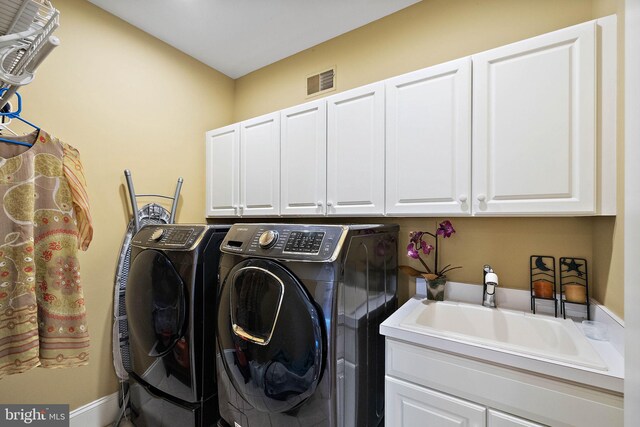 laundry room with cabinets, washing machine and clothes dryer, and sink