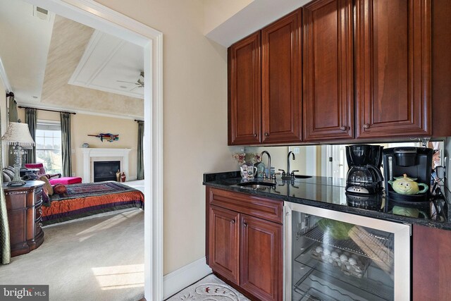 kitchen with a raised ceiling, wine cooler, sink, light colored carpet, and ceiling fan