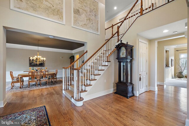 stairs featuring crown molding, a high ceiling, and hardwood / wood-style flooring