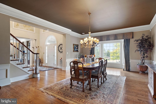 dining space with hardwood / wood-style flooring, a notable chandelier, and ornamental molding