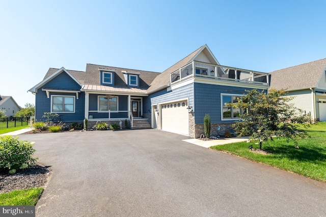 craftsman house featuring a garage, a balcony, stone siding, aphalt driveway, and a standing seam roof