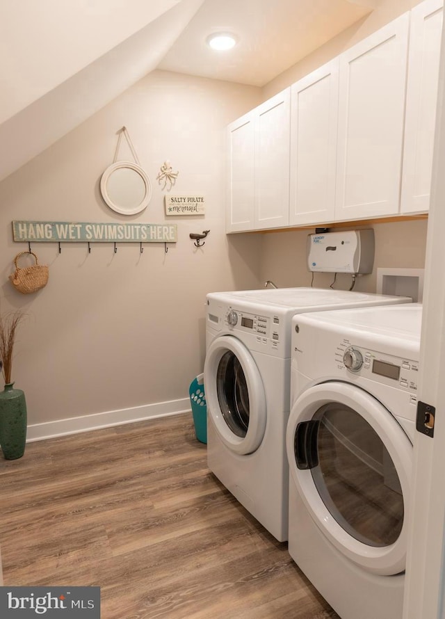 washroom with hardwood / wood-style flooring, cabinets, and washer and dryer