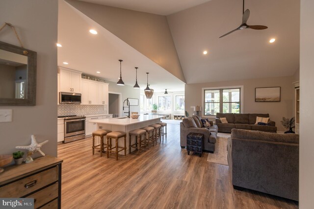 living room with hardwood / wood-style floors, high vaulted ceiling, sink, and ceiling fan