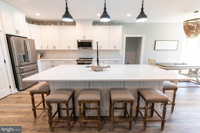 kitchen with appliances with stainless steel finishes, white cabinetry, and an island with sink