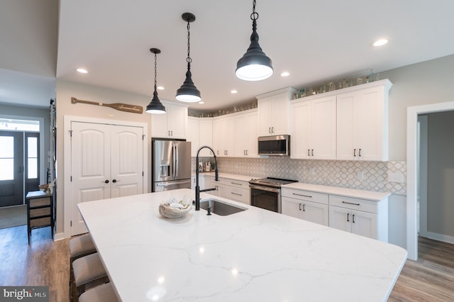 kitchen with pendant lighting, white cabinetry, stainless steel appliances, and sink