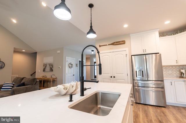 kitchen with vaulted ceiling, decorative light fixtures, stainless steel fridge with ice dispenser, light hardwood / wood-style floors, and white cabinets