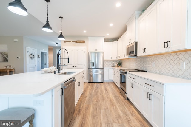 kitchen featuring white cabinets, hanging light fixtures, stainless steel appliances, and sink