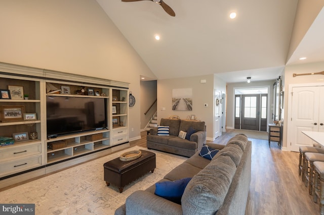 living room with high vaulted ceiling, ceiling fan, and light wood-type flooring