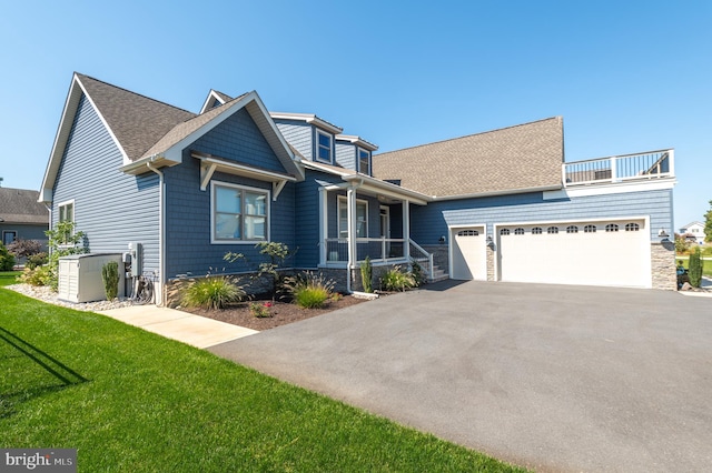 view of front of house featuring aphalt driveway, roof with shingles, covered porch, a garage, and a front lawn