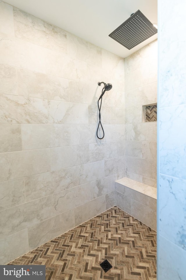 bathroom with a tile shower and parquet flooring