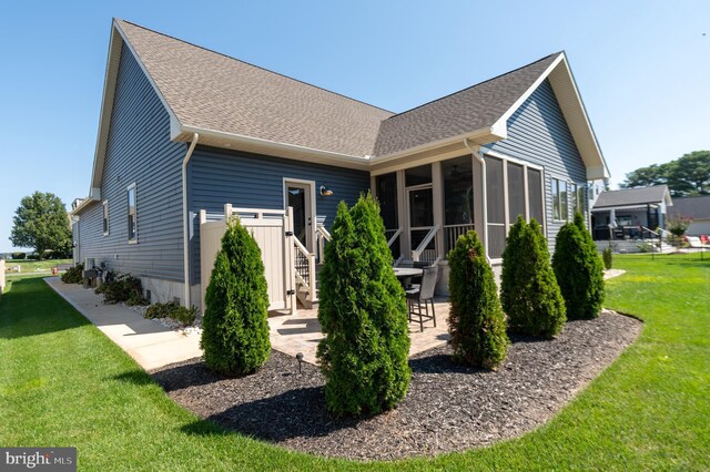 back of house featuring a lawn and a sunroom