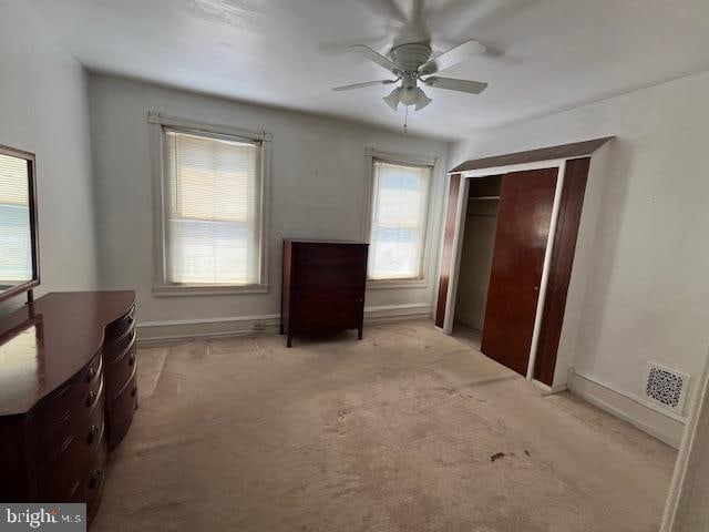 carpeted bedroom with ceiling fan, a closet, and multiple windows