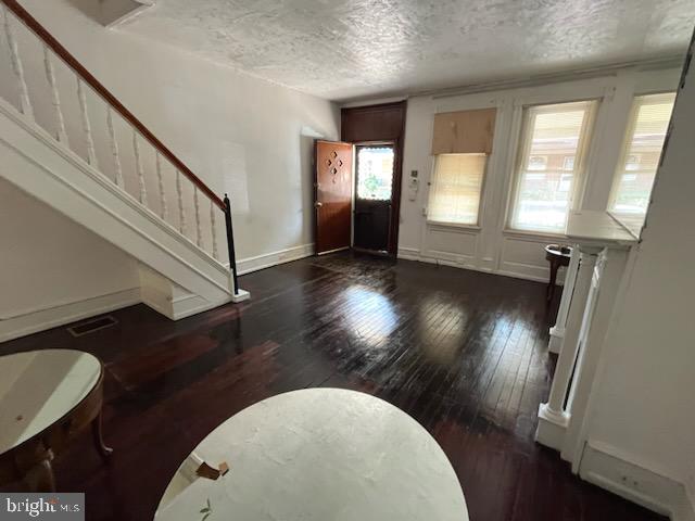 foyer with a textured ceiling and dark wood-type flooring