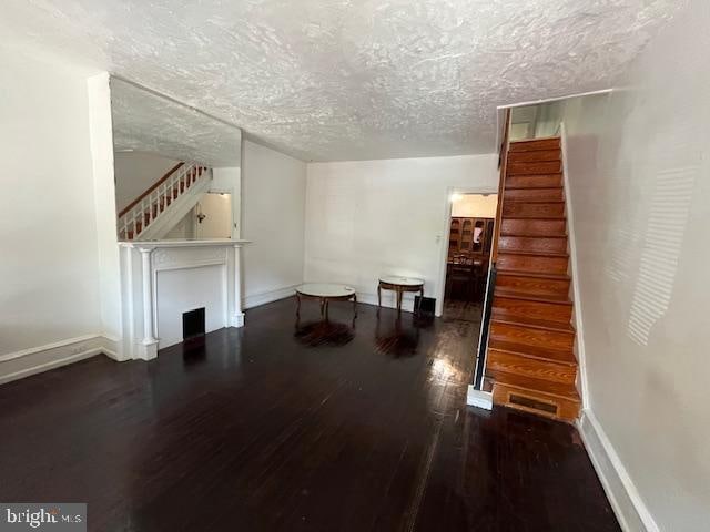 unfurnished living room with dark hardwood / wood-style flooring and a textured ceiling