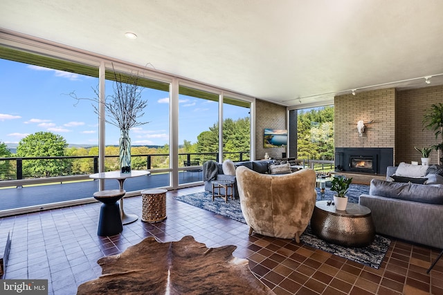 sunroom / solarium featuring plenty of natural light, track lighting, and a fireplace