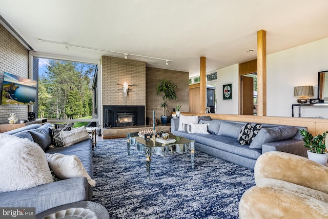 living room with brick wall, a large fireplace, and rail lighting