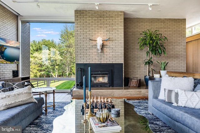 living room featuring track lighting, floor to ceiling windows, and brick wall