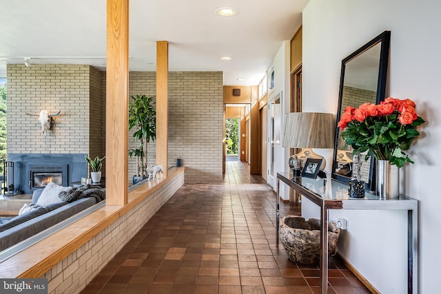 hallway with brick wall and dark tile patterned flooring