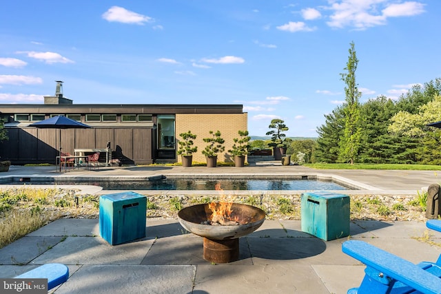 view of swimming pool featuring an outdoor fire pit and a patio