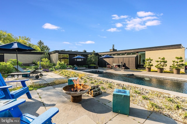 view of pool with an outdoor fire pit and a patio