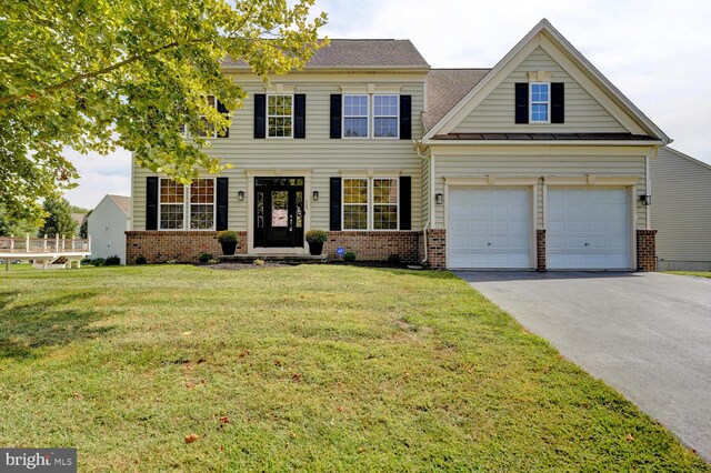 colonial house featuring driveway, a garage, brick siding, roof with shingles, and a front yard