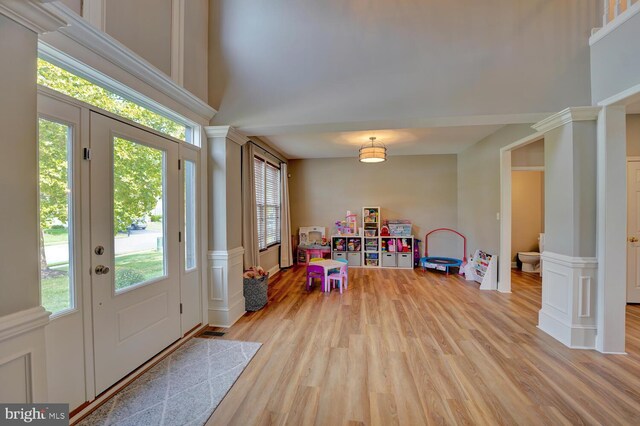 foyer featuring light wood-type flooring, ornate columns, and a towering ceiling