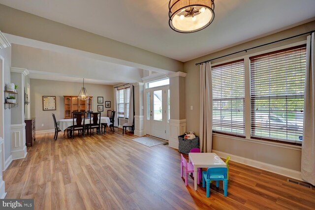 foyer entrance with baseboards, light wood-type flooring, visible vents, and an inviting chandelier