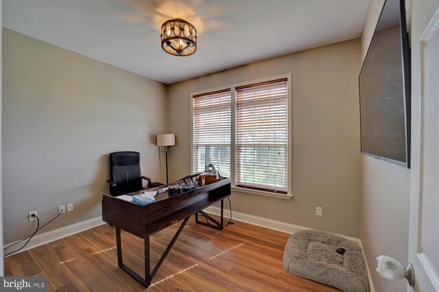 home office with an inviting chandelier, wood finished floors, and baseboards