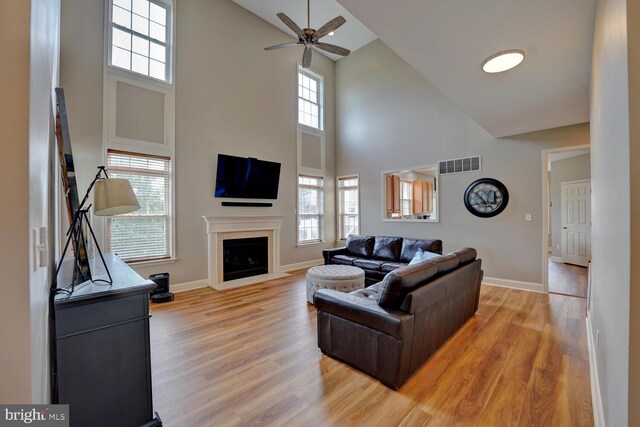 living area featuring light wood finished floors, a fireplace, visible vents, and baseboards