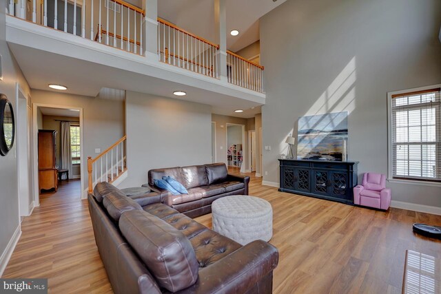 living room with stairs, a high ceiling, wood finished floors, and baseboards