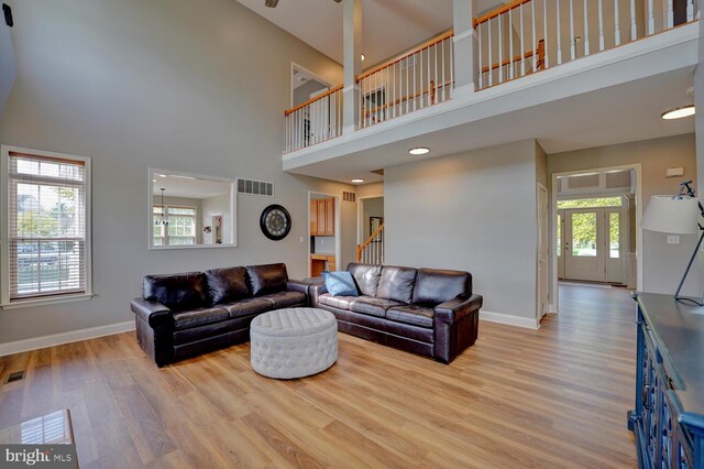 living room with stairs, wood finished floors, visible vents, and baseboards