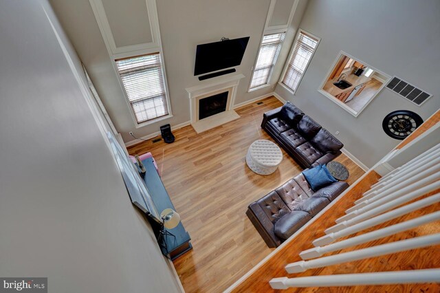 living room with a fireplace with flush hearth, visible vents, plenty of natural light, and wood finished floors