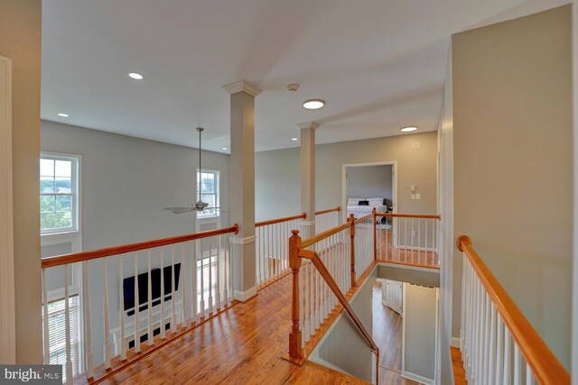 hall with recessed lighting, wood finished floors, an upstairs landing, baseboards, and decorative columns