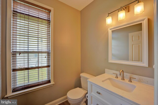 bathroom featuring toilet, baseboards, and vanity